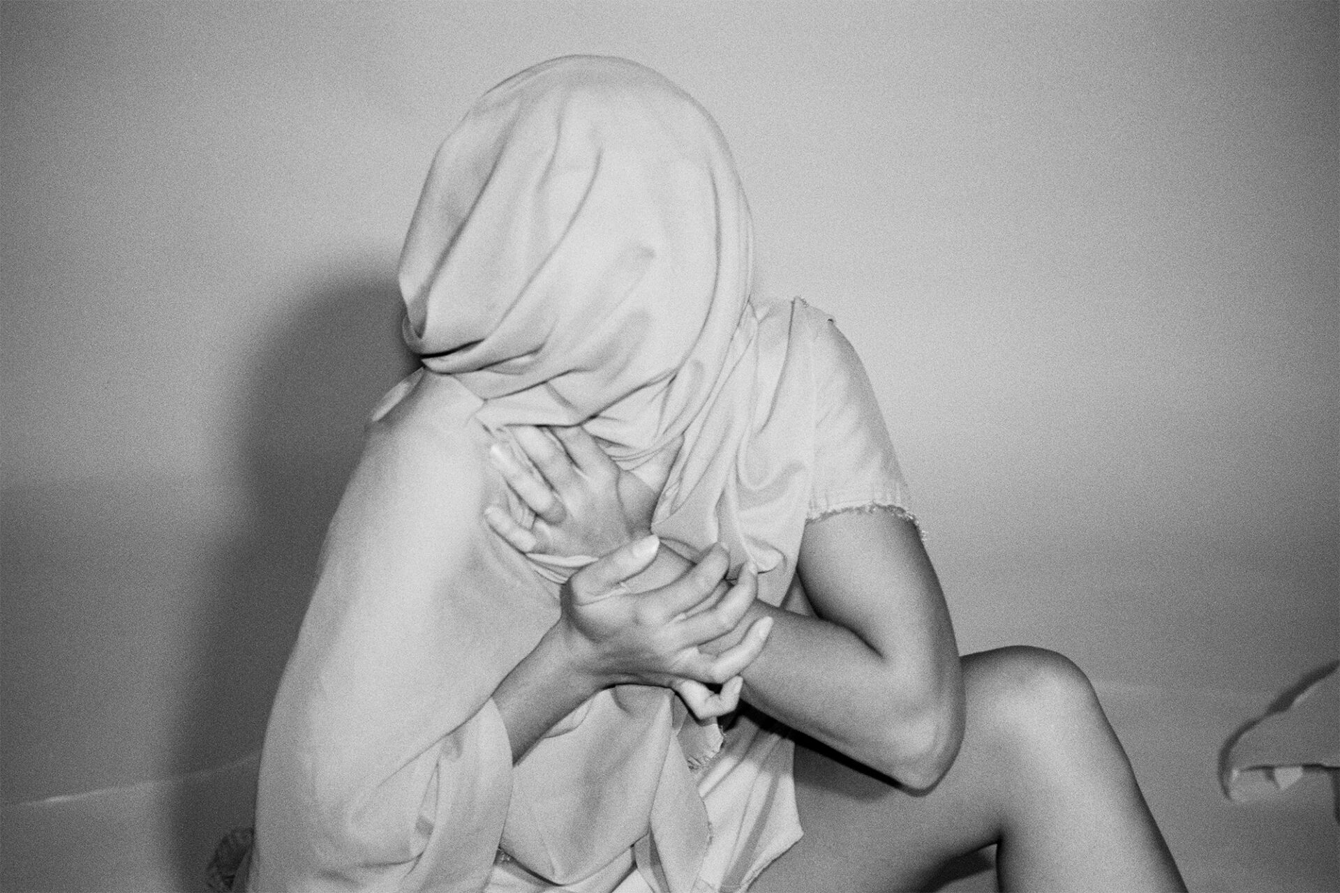 A Syntactical Drip By Jenica Heintzelman. This photograph depicts a woman wrapped up in cloth while sitting down